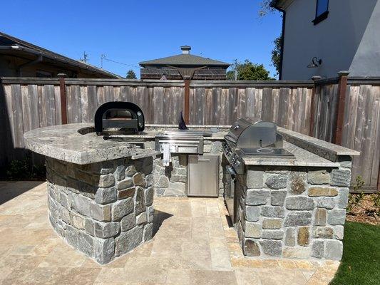 Outdoor kitchen with natural stone walls.