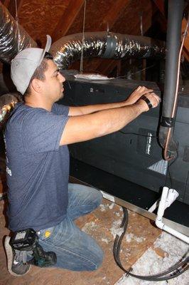 Technician finishing up an air handler in an attic.