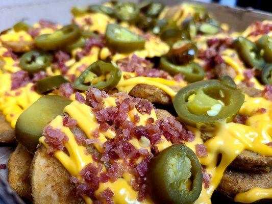 RED's Nacho Potatoes - Our potato rounds smothered in nacho cheese, topped with bacon bits and jalapenos.