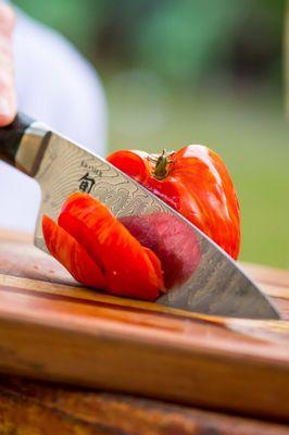 A mirror finished sharpened knife, on the Wicked Edge Professional System, slicing through a over ripened tomato.