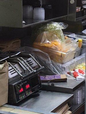 CHeese and lettuce removed from temperature controlled bins and they are using plastic covering the food preparation area.