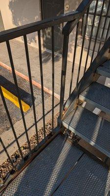 Rusted handrail with holes. Where the metal plate is, the metal railing has broken apart and they put that on to hold it together.