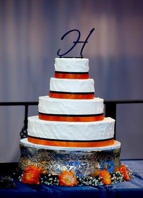 White cake with textured icing and ribbon trim.