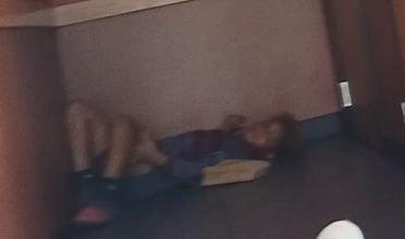 Child laying in the floor by the restrooms.