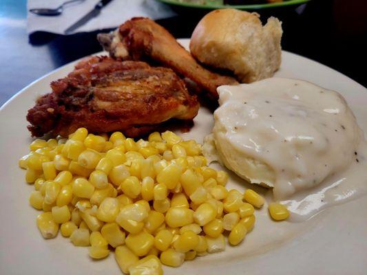 Fried chicken,  corn, mashed potatoes and gravy, and a roll.