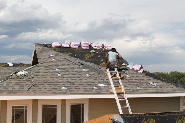 Roofers repairing a storm damaged roof in Denver, CO