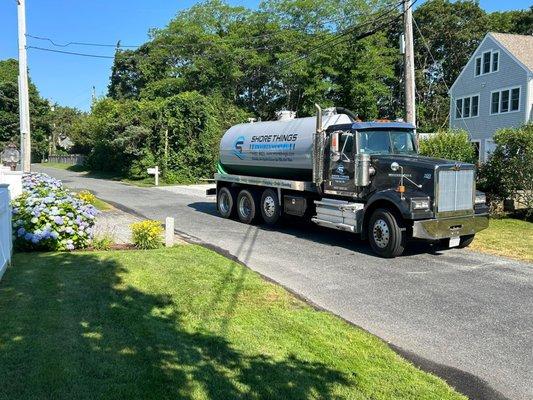 Shore Things Environmental septic truck in front of a house with trees in background and green grass in foreground