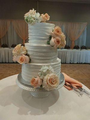 Simple and elegant three tier cake with fresh roses.  Iced with butter cream icing.