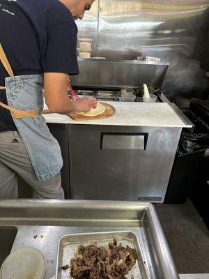 Guillermo preparing a short rib sandwich.