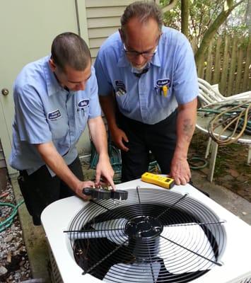 Bill and Michael check the refrigerant charge on an air conditioner.