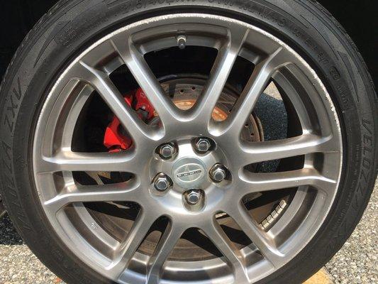 17" low profile tires on stock alloy rims, with aftermarket drilled and slotted rotors, paired with red calipers.