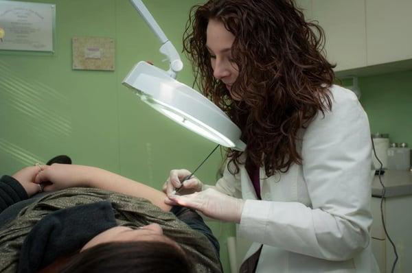 Katie performing an Electrology service on a client's arm. Call today for a FREE consultation on Electrology!