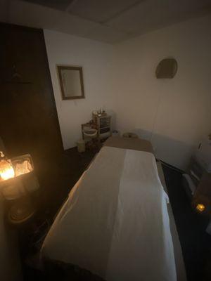 Massage Room with candles, Himalayan salt lamp and a client station with a phone charger, facial spray, mints and a mirror