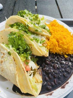 Three chicken tacos with black beans and yellow rice.