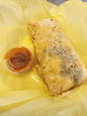 Machaca and egg burrito compared to the salsa container. Note the oil or grease on the wrapper and tortilla.