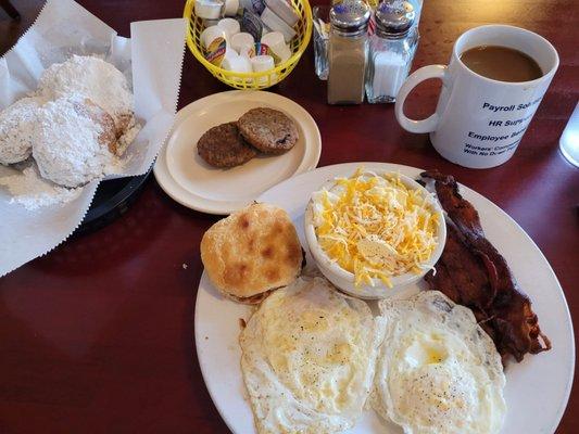 Beignets, eggs, bacon, cheese grits, biscuit, sausage and coffee