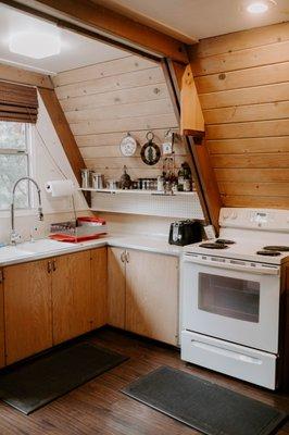 Idyllcreek's open kitchen is well stocked with cooking utensils, an electric stove, and toaster.