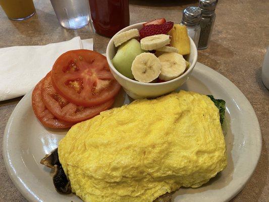 Three egg omelette with pepper Jack cheese broccoli sausage and mushrooms. Sliced tomatoes and fruit cup instead of toast and potatoes.