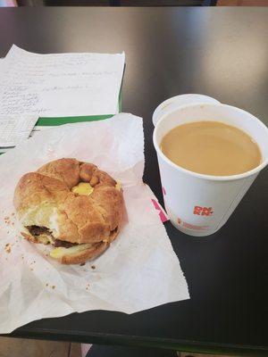 Egg sausage and cheese breakfast sandwich on a croissant and coffee