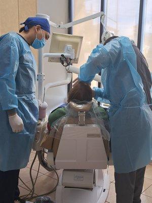 A dentist and his dental assistant working a treatment plan with a patient. Feb 2023