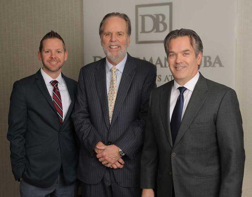 Partners of Doehrman Buba Ring Car Accident & Personal Injury Lawyers standing in their office lobby in front of the firm's signage