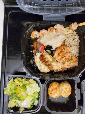 Lobster tail, baked salmon with rice pilaf and a shrimp skewer with salad