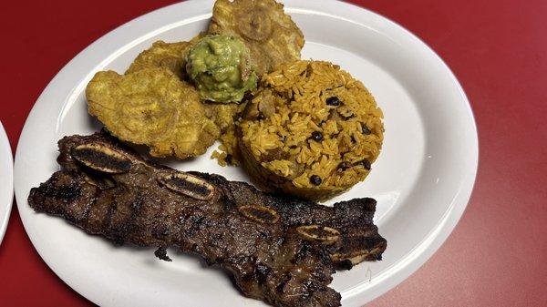 Costilla de Res with Arroz de gandules and Tostones topped with Guac