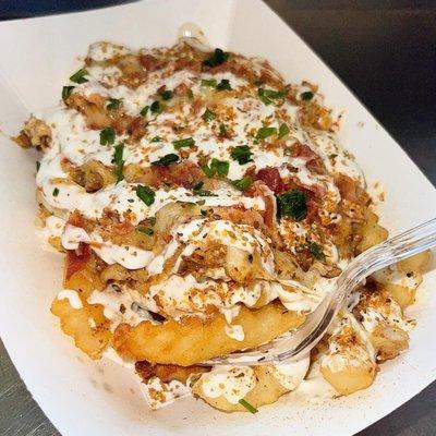 Rajun Cajun Fries (Golden fries topped with Cajun seasoned chicken, melted cheese, ranch, Cajun seasoning, bacon, and green onion.)