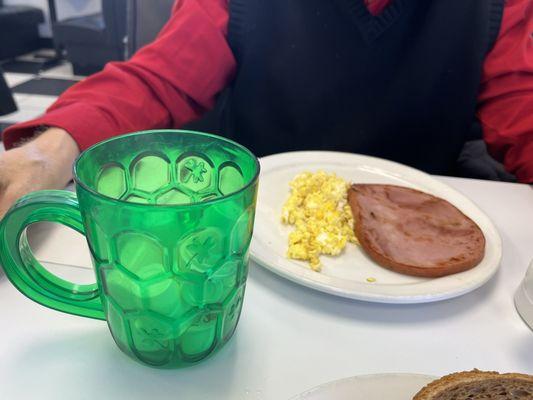 Ham steak and scrambled eggs, green cup filled with variety of creamers!