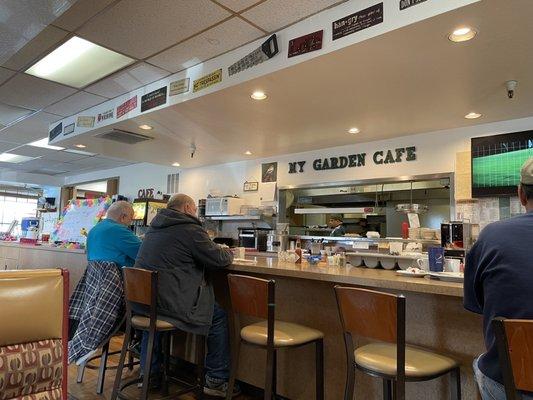 Counter regulars engaging in conversation with the chef made me smile even more than the funny sign decor.