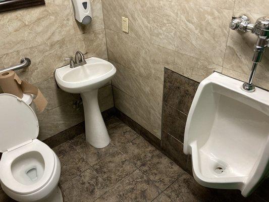 tiny men's restroom, with sink located between toilet and urinal