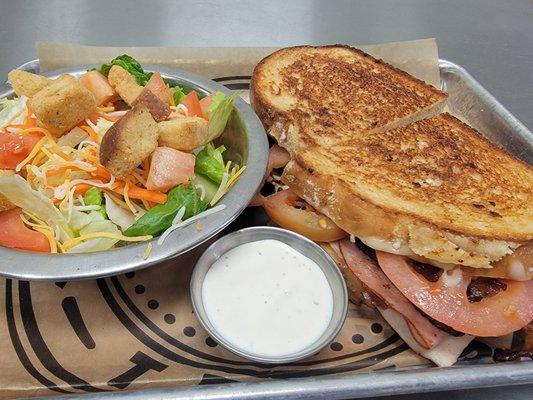 Grilled club sandwich with a side house salad.