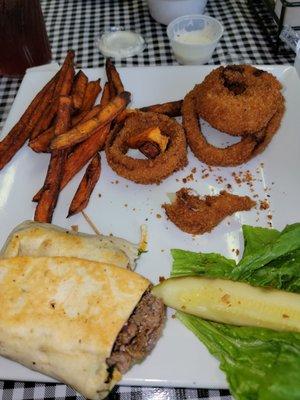 Steak wrap with side of onion rings and potato fries