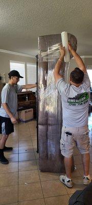 Ben and Chris wrapping a section of a couch.