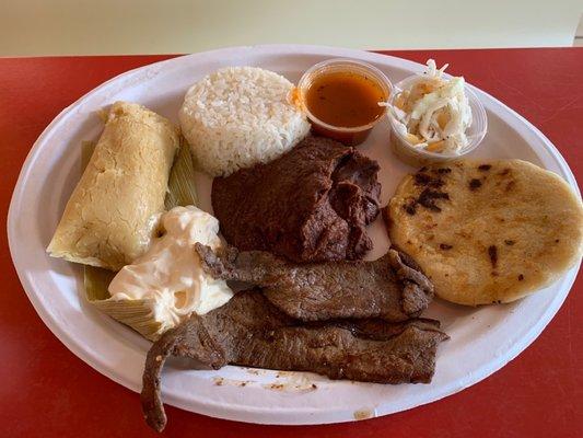 Combination plate with rice, beans, steak, cream, tamale, and pupusas