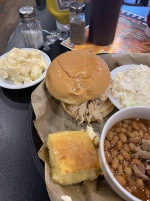 Pulled chicken sandwich, potato salad, baked beans, coleslaw,, and cornbread.