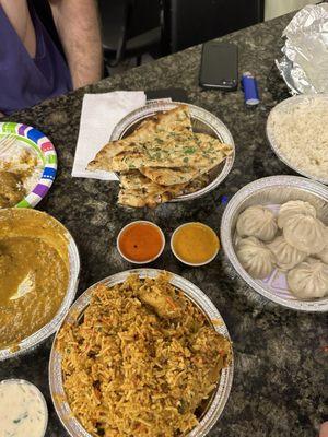 Chicken Biryani (bottom), momos (right) , garlic naan (top), beef korma (left)