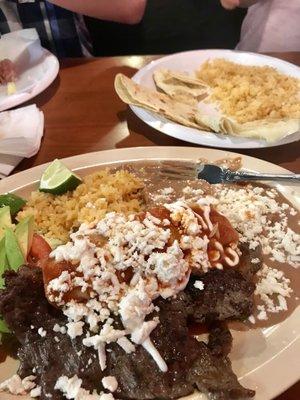 carne asada served with an enchilada and rice and beans. On the far side is my daughters quesadilla and rice she ate all of it!