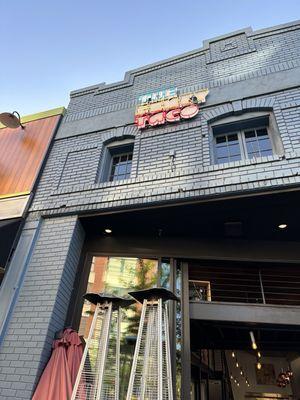 Gray brick building with The Funky Taco neon lit sign