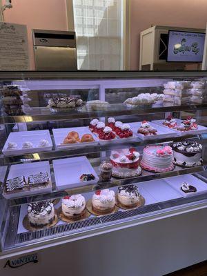 Display case with whole cakes, cheesecakes, and pie slices