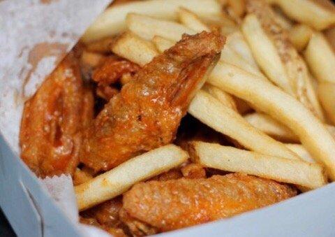 Medium sauced wings and French Fries in their signature white to go box.