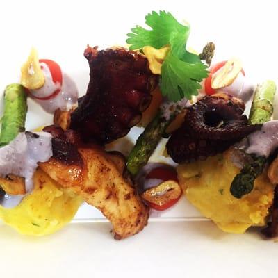 Grilled octopus and asparagus on a yellow pepper, lime juice, potato rough mash with cherry tomatoes, garlic chips, and olive aioli