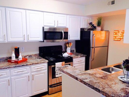 Updated kitchens with stainless steel appliances and white cabinetry.