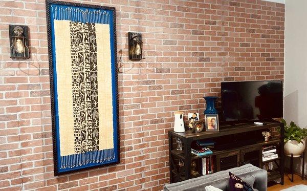 Custom 5.5ft framing of scarf in black textured frame on blue matting. Entertainment center along side for size reference.