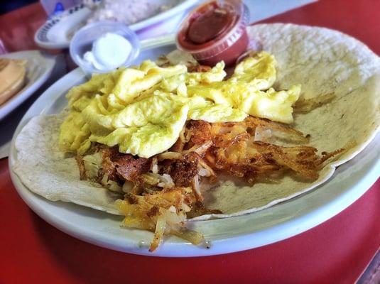 Huevos Rancheros: Crispy Hash Browns on a Tortilla topped with Cheese & Two Eggs, Sour Cream & Salsa.