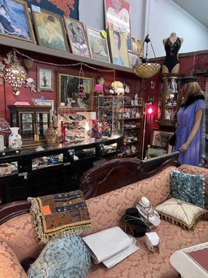 An art deco canoe shaped display cabinet with knives, fountain pens, commercial perfume set, sterling flatware, and more