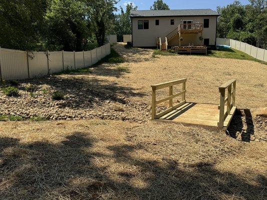 Wooden bridge over dry creek bed.  Drainage area for a large sloped back yard