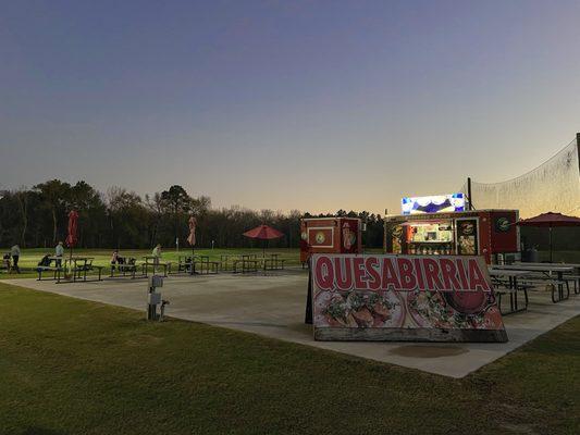 The truck is parked on a concrete pad adjacent to a golf driving range. It is clean and well-lit.