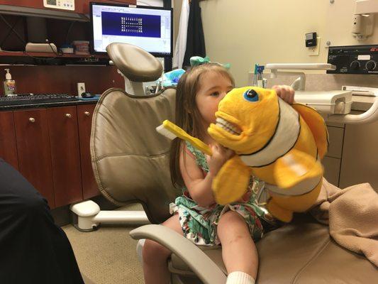 Family-friendly dental office with Nemo assisting with tooth brushing instruction.