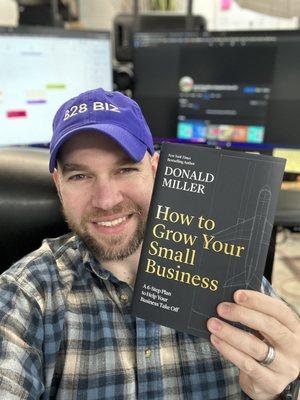 Andrew Murkens, owner at 828 Biz holding a great book for small businesses, "How to Grow Your Small Business" by Donald Miller